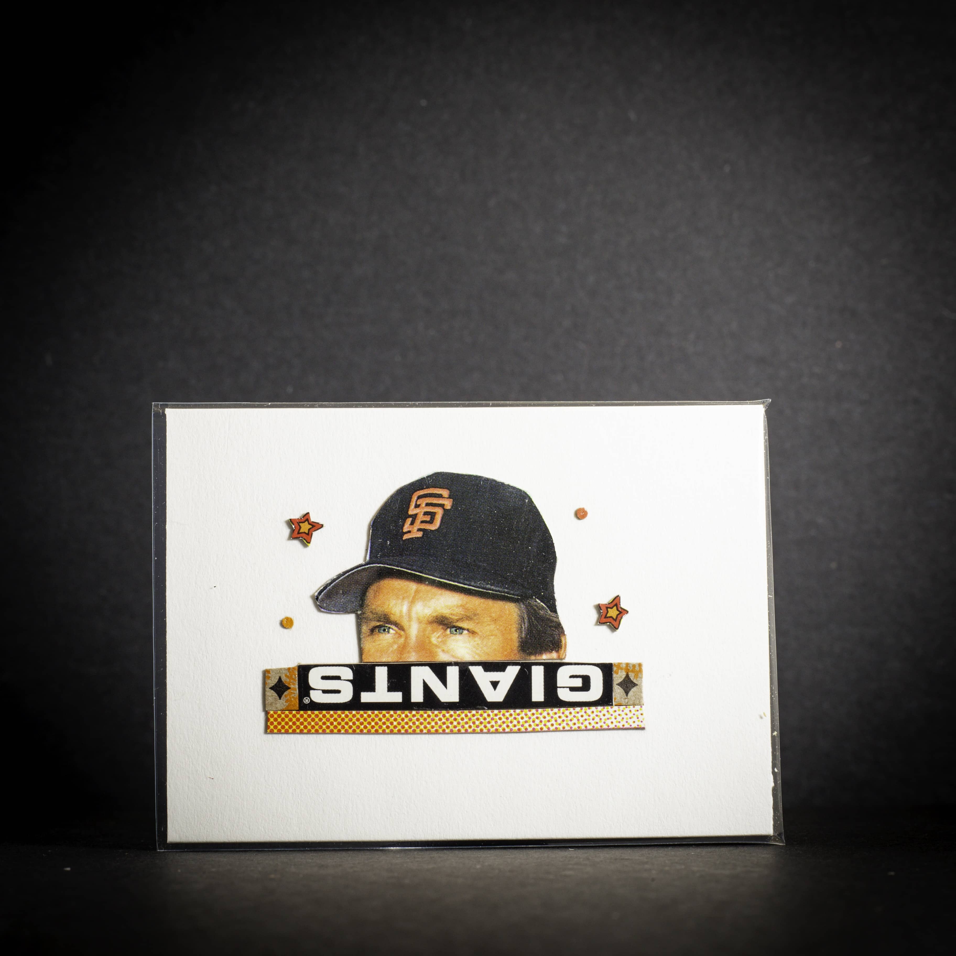 Card with a baseball player wearing a Giants cap on a dark background