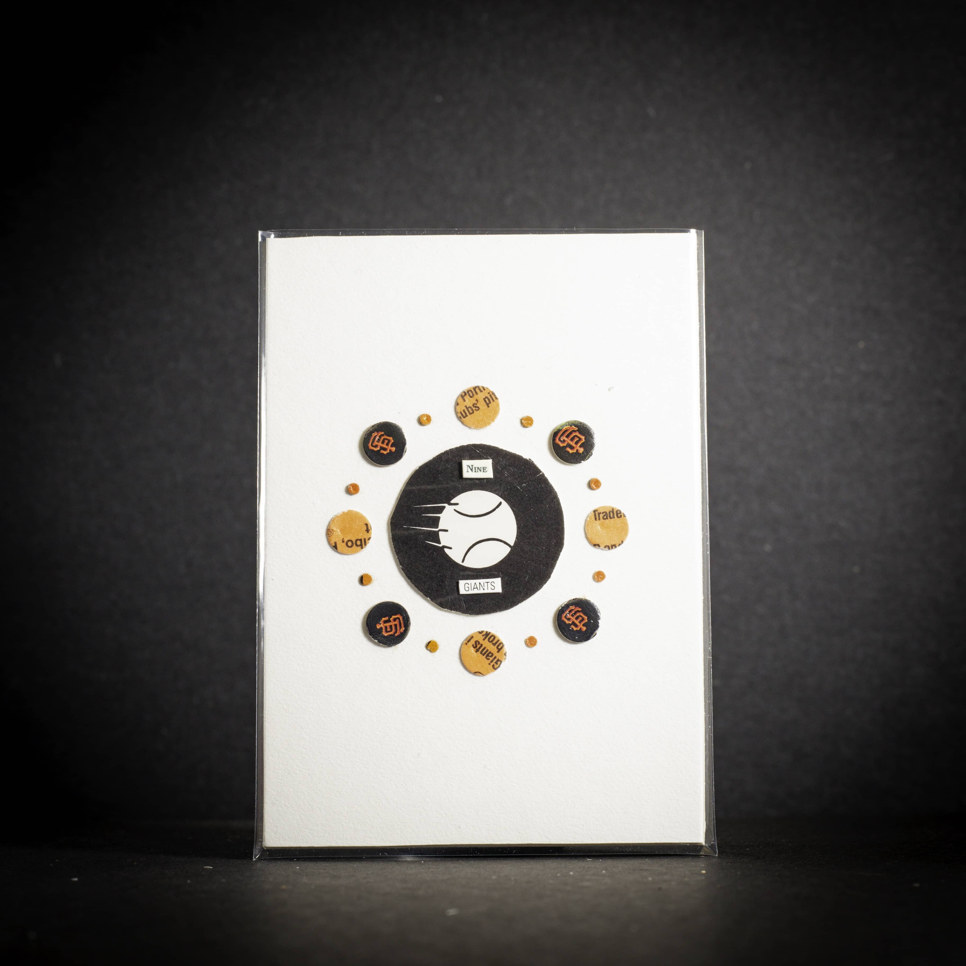 Collection of baseball-themed pins on a white card with a black border against a dark background