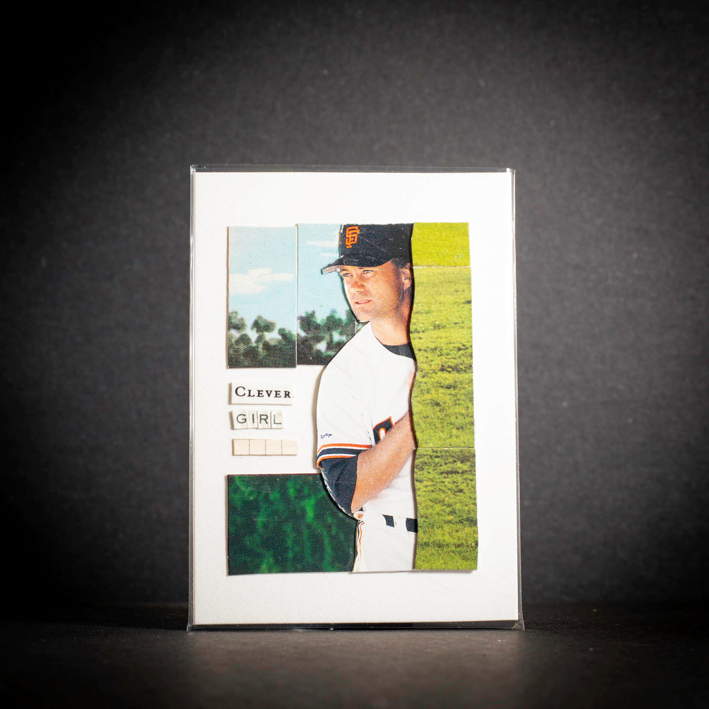 Baseball card of a player in a white uniform with a dark cap on a dark background