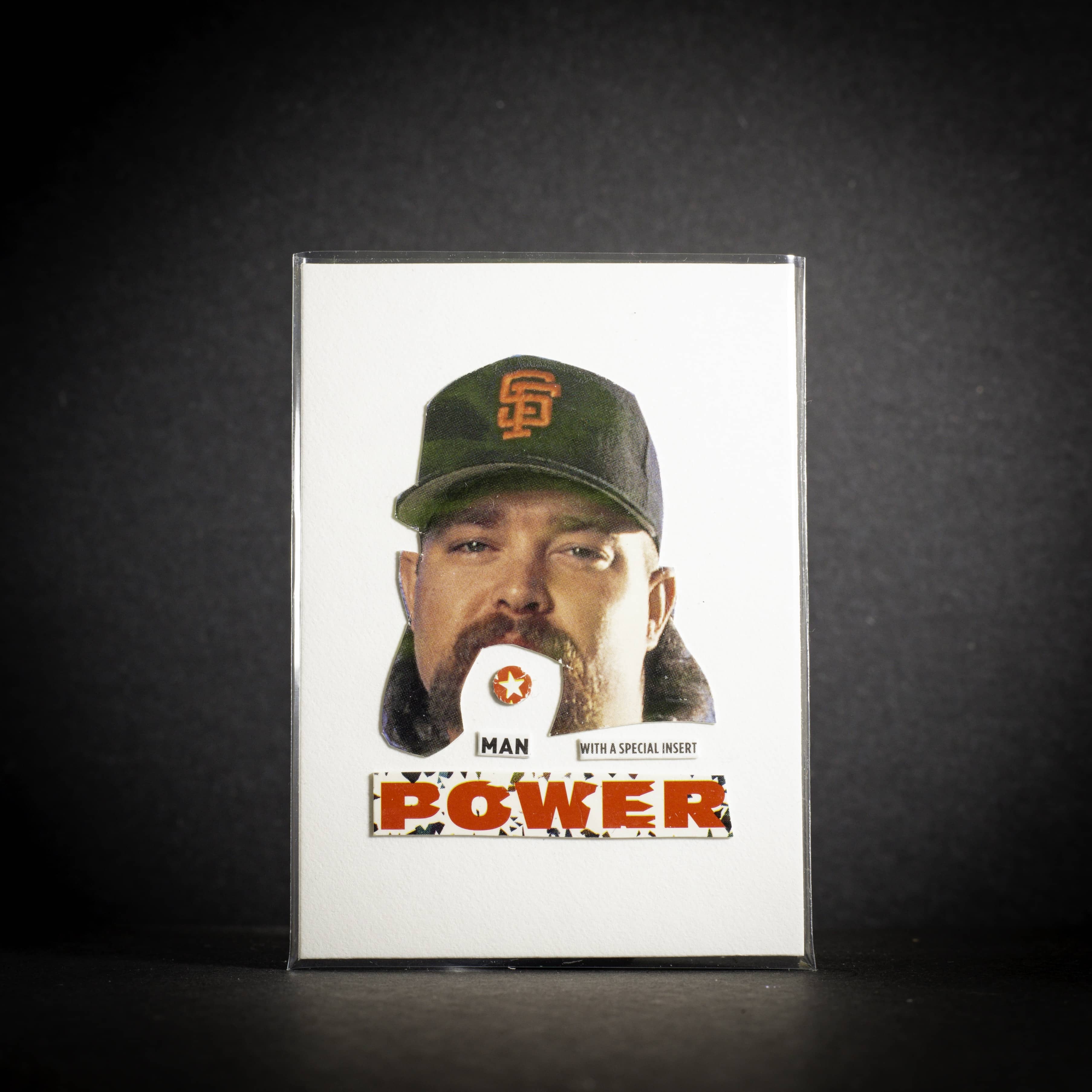 Trading card of a person wearing a cap with a logo, on a dark background